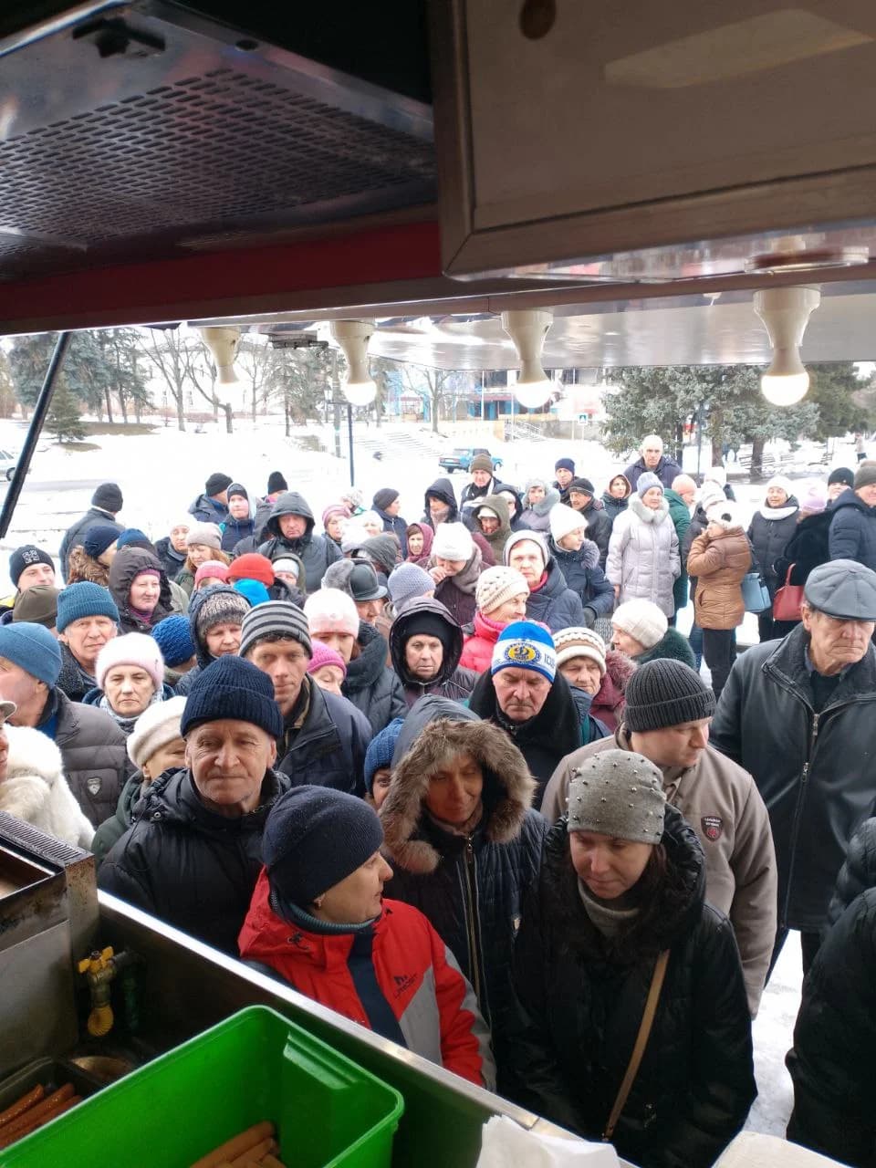 Селище Куп'янськ-Вузловий, центральна площа, кінець осені 2023 року. Проєкт Food Truck: цивільне населення в черзі за гарячою їжею. Видачу організували волонтери XTRAVERSE за підтримки Yapiko та БФ «АртДача».
