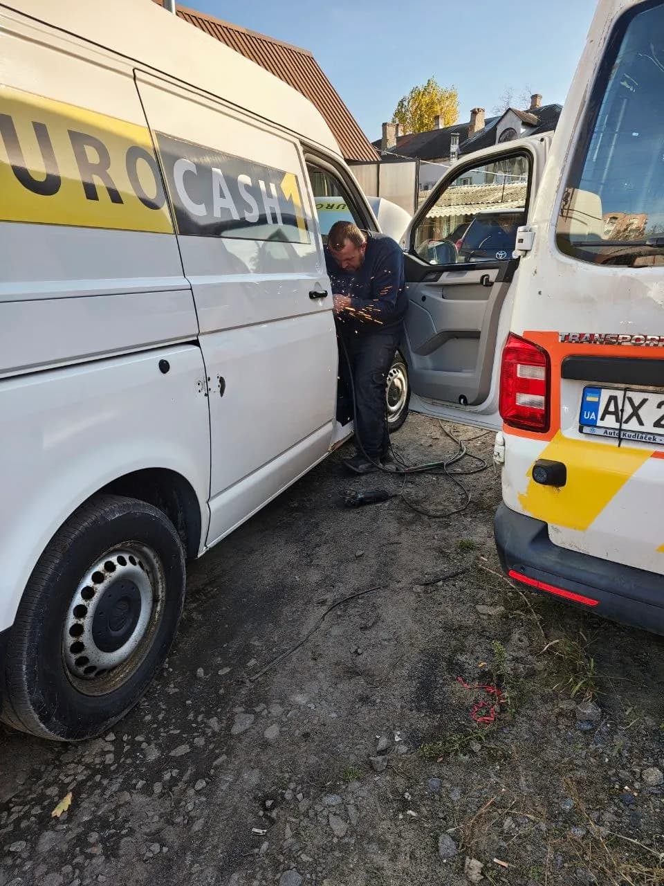 A new light-armoured T6 has arrived for evacuations 🙏⚡💪: a man with an angle grinder cutting metal between two white vans in a yard, sparks flying through the air - Xtraverse